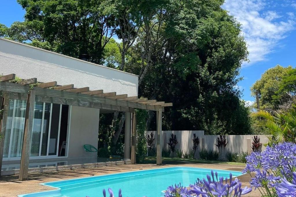 una piscina frente a una casa con pérgola de madera en Quinta do Trevo, en Chapecó