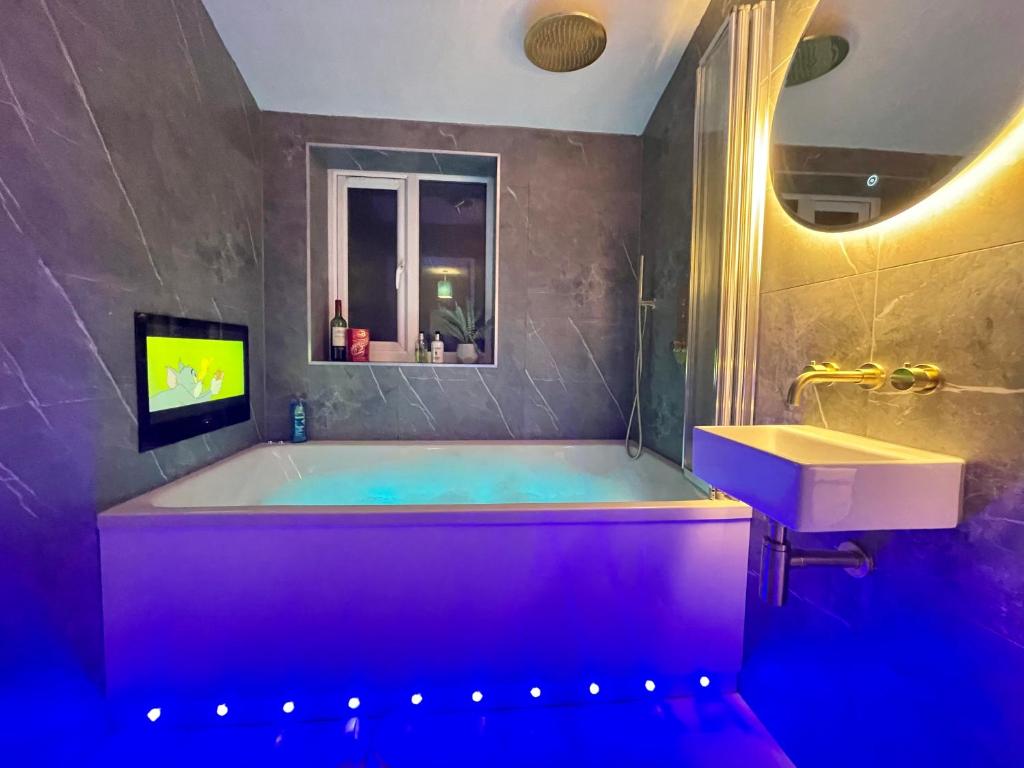 TV y baño con bañera y lavabo. en Coastline Retreats - Newly Refurbished Town centre, Close to beach, Large Jet bath with TV, Netflix, swing and we pay parking en Bournemouth