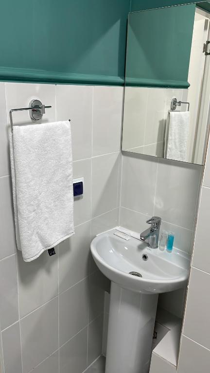 ein weißes Badezimmer mit einem Waschbecken und einem Spiegel in der Unterkunft Жилой Комплекс Акжайык in Astana