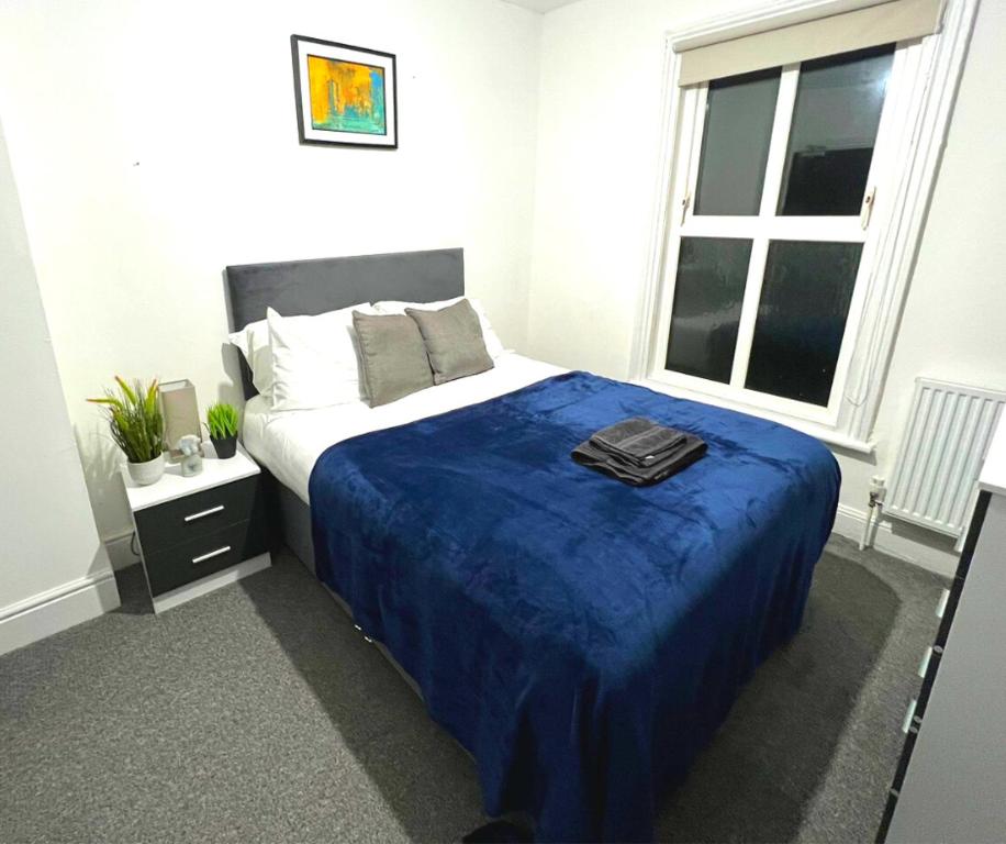 a bedroom with a bed with a blue blanket at Chantry Suites in Grimsby