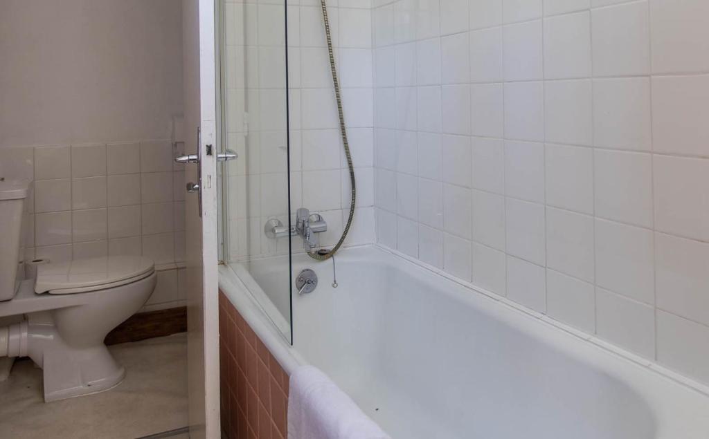 a bathroom with a bath tub and a toilet at Hotel Le Chamois in L&#39;Alpe-d&#39;Huez