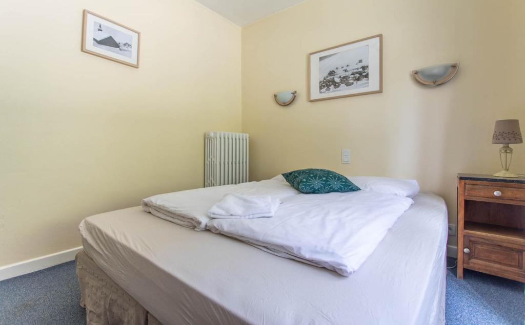 a small bedroom with a bed and a dresser at Hotel Le Chamois in L&#39;Alpe-d&#39;Huez