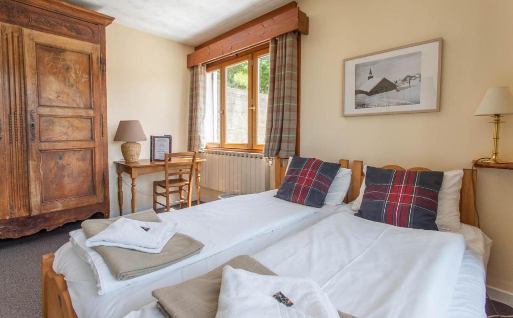 a bedroom with two beds and a table and a window at Hotel Le Chamois in L&#39;Alpe-d&#39;Huez