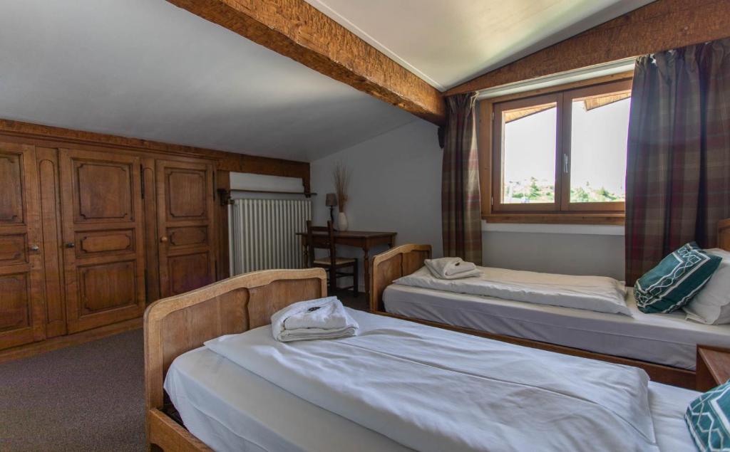 a bedroom with two beds and a window at Hotel Le Chamois in L&#39;Alpe-d&#39;Huez