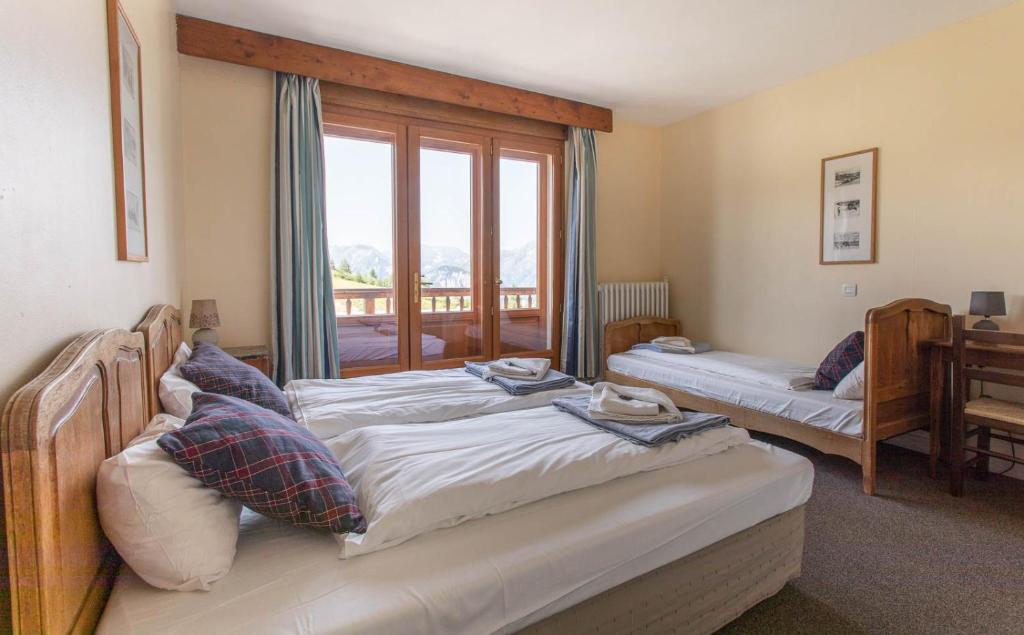 two beds in a room with a window at Hotel Le Chamois in L&#39;Alpe-d&#39;Huez