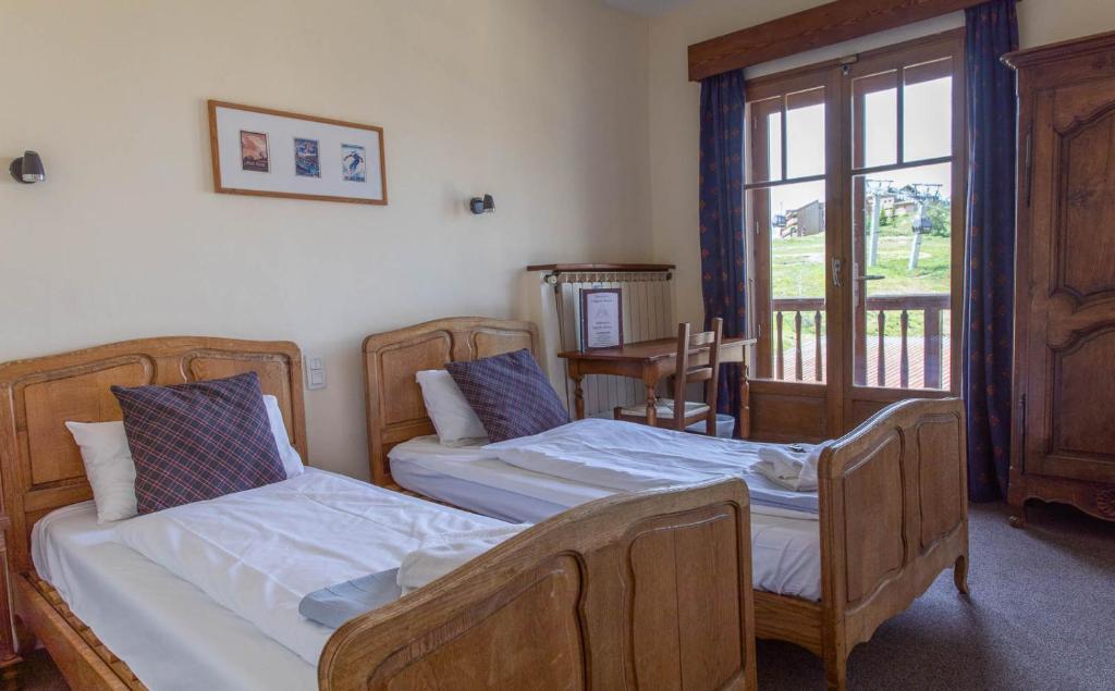 a bedroom with two beds and a window at Hotel Le Chamois in L&#39;Alpe-d&#39;Huez