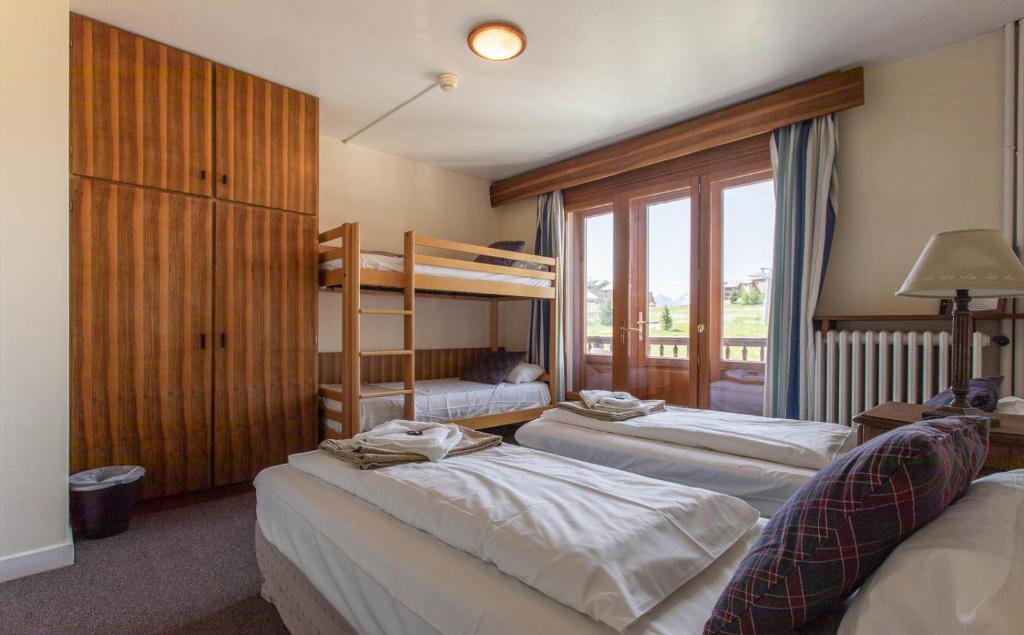a bedroom with two bunk beds and a window at Hotel Le Chamois in L&#39;Alpe-d&#39;Huez