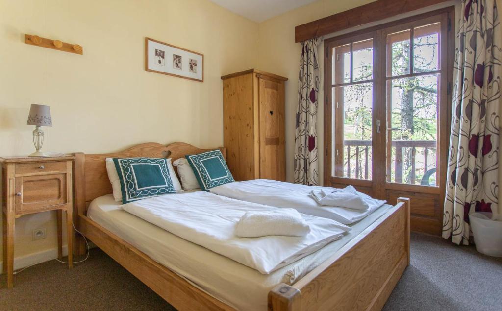 a bedroom with a bed with a wooden headboard and a window at Hotel Le Chamois in L&#39;Alpe-d&#39;Huez