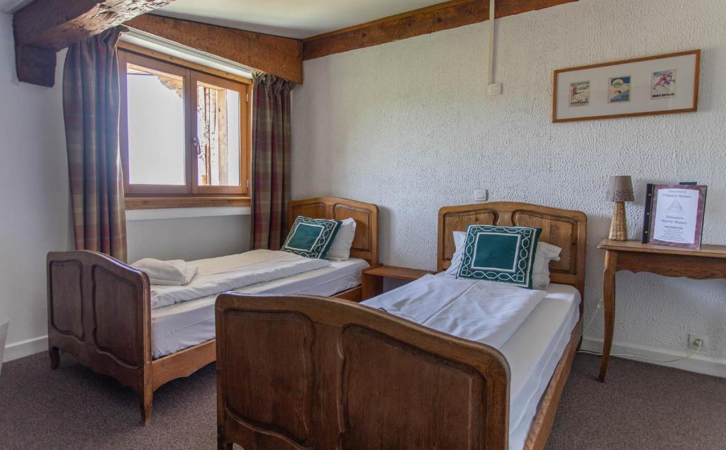 a room with two beds and a window at Hotel Le Chamois in L&#39;Alpe-d&#39;Huez