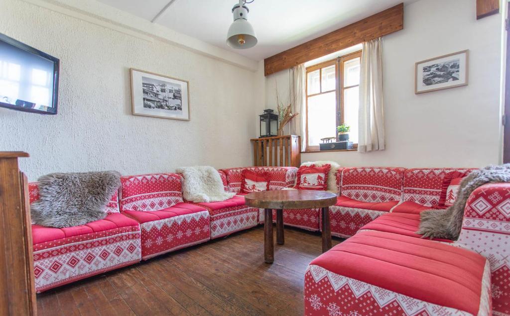 a living room with red couches and a table at Hotel Le Chamois in L&#39;Alpe-d&#39;Huez