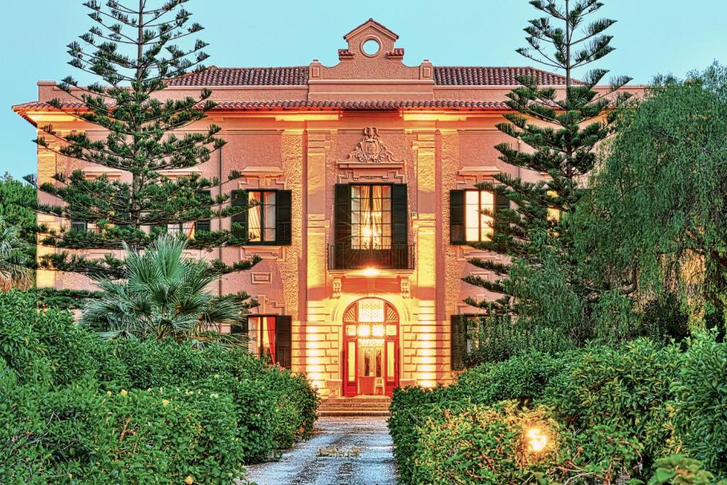uma grande casa de tijolos com árvores em frente em Villa Angelina - charming rooms & apartments em Trapani