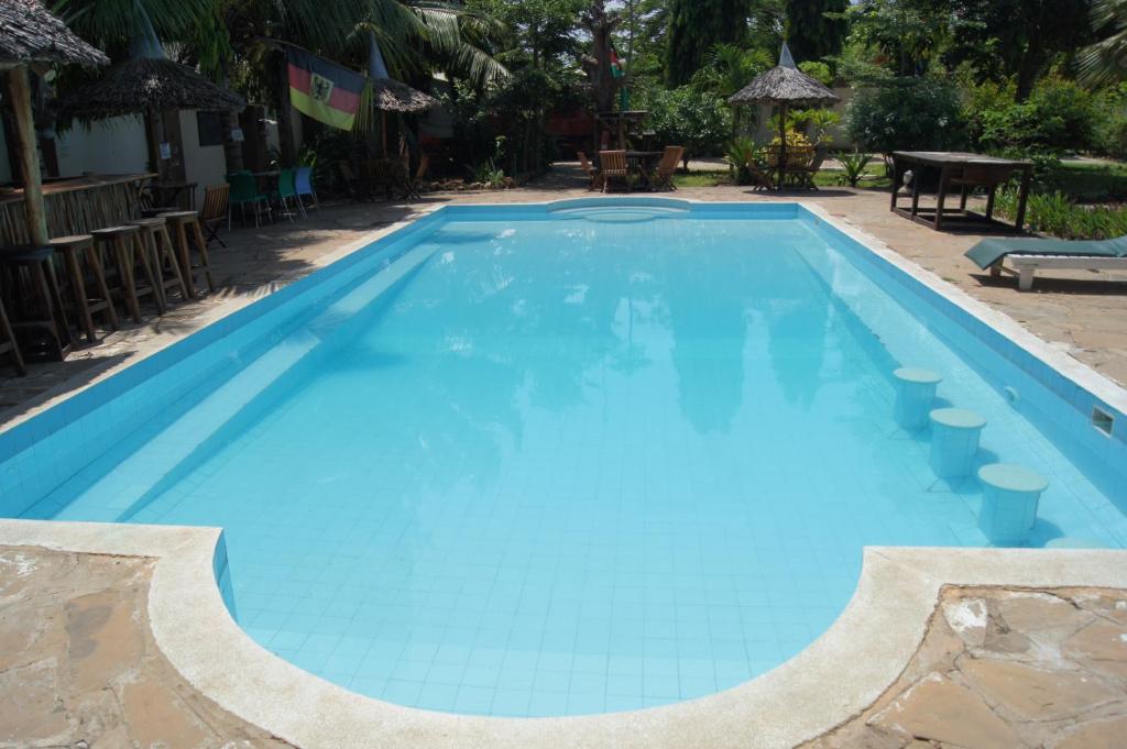 una gran piscina azul con mesa y sillas en Tulia House Backpackers, en Mombasa