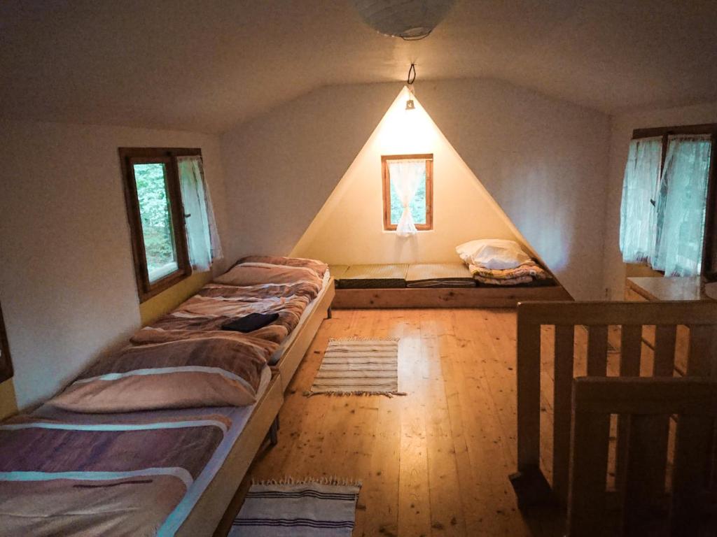 a bedroom with two beds in a room with a roof at Roztomilá a utulná chata Azzy na samotě v lese. in Valašské Klobouky