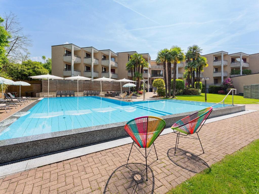 einem Pool mit zwei Stühlen vor einem Gebäude in der Unterkunft Apartment Resort al Centro-3 by Interhome in Massagno