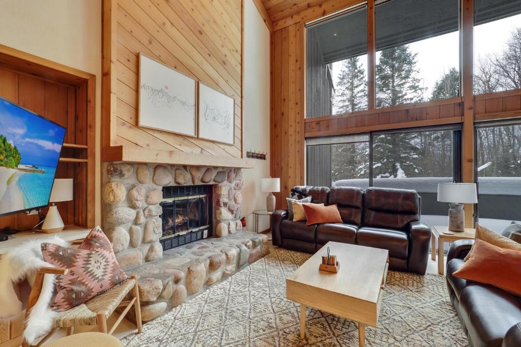 a living room with a stone fireplace and leather furniture at The Hidden Chalet in Harbor Springs