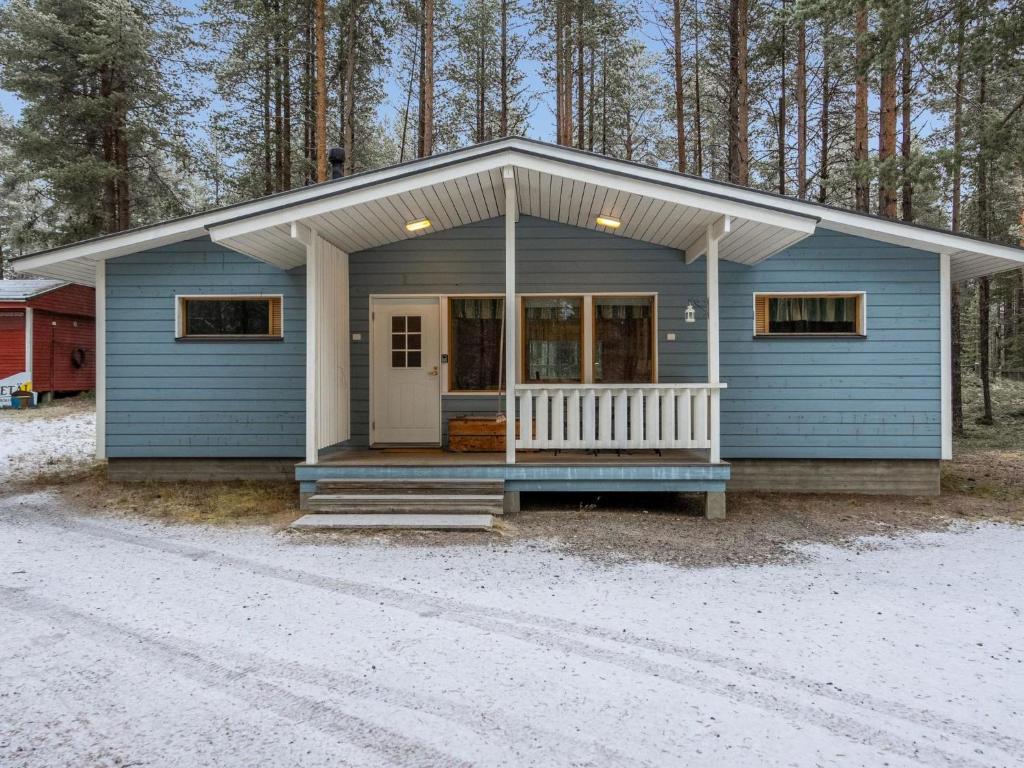 a blue tiny house with a porch in the woods at Holiday Home Villa kuusanka by Interhome in Kuusamo