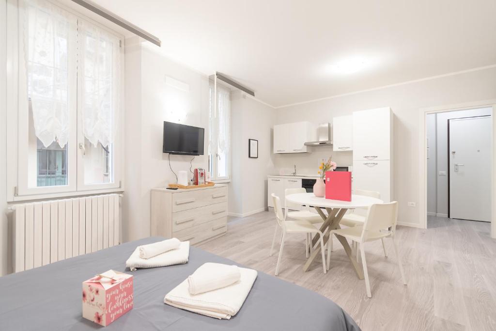 Ein weißes Zimmer mit einem Tisch und ein Zimmer mit einer Küche. in der Unterkunft Palazzetto Vittoria - F&L Apartment in Brescia