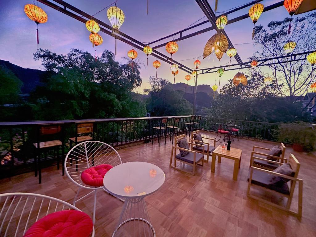 un patio con mesas, sillas y luces chinas en Trang An Moon Garden Homestay en Ninh Binh