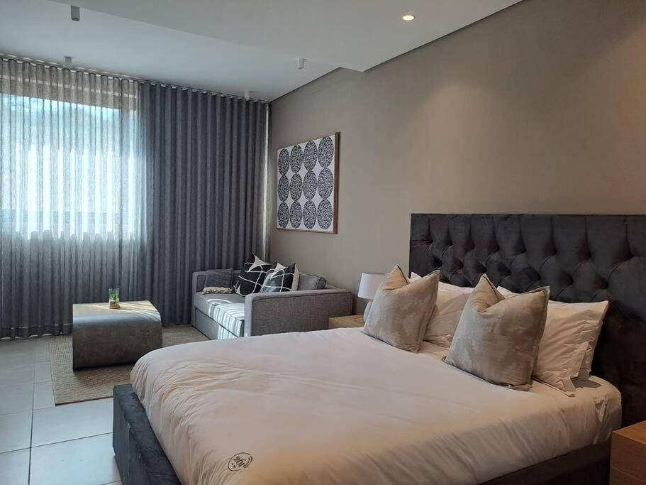 Un dormitorio con una cama grande y una sala de estar. en Zimbali Lakes Boulevard Suites 261, en Ballito