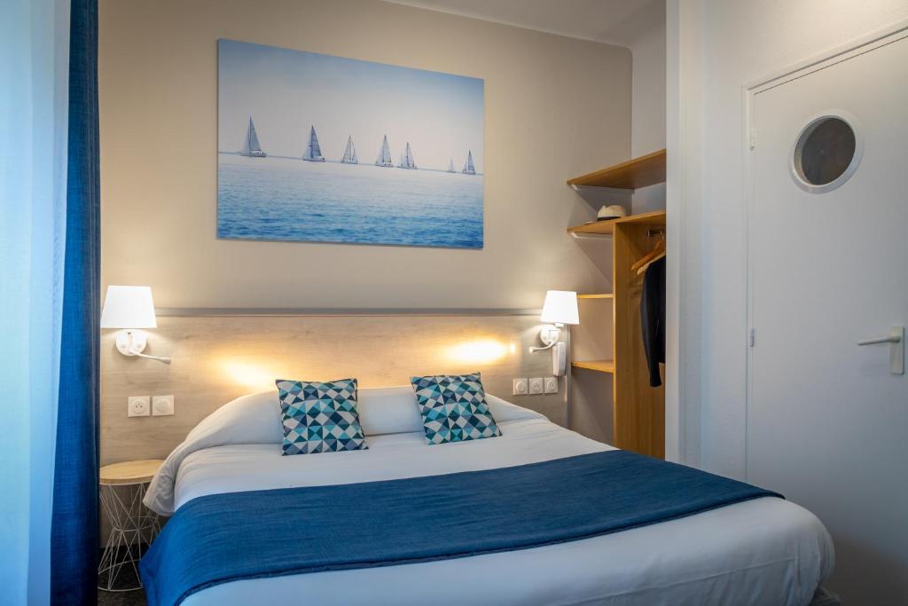 um quarto com uma cama com duas almofadas azuis em Logis REX HOTEL Lorient em Lorient