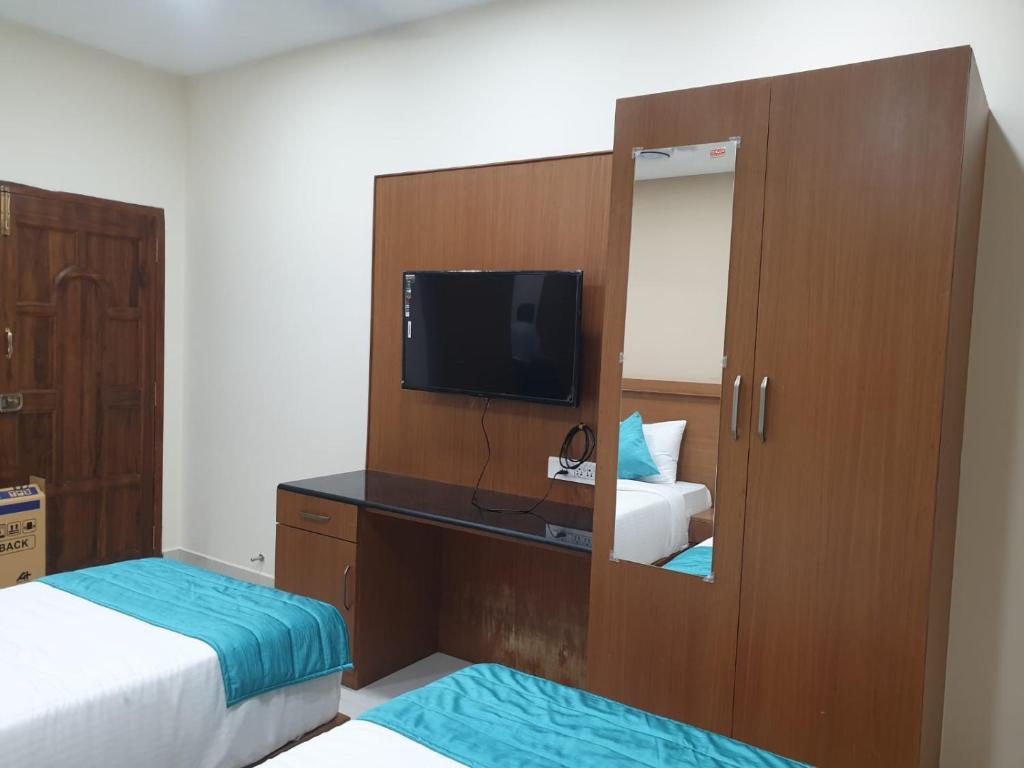 a room with two beds and a tv and a mirror at Kanmani Elite- A Perfect Home in Tiruchirappalli