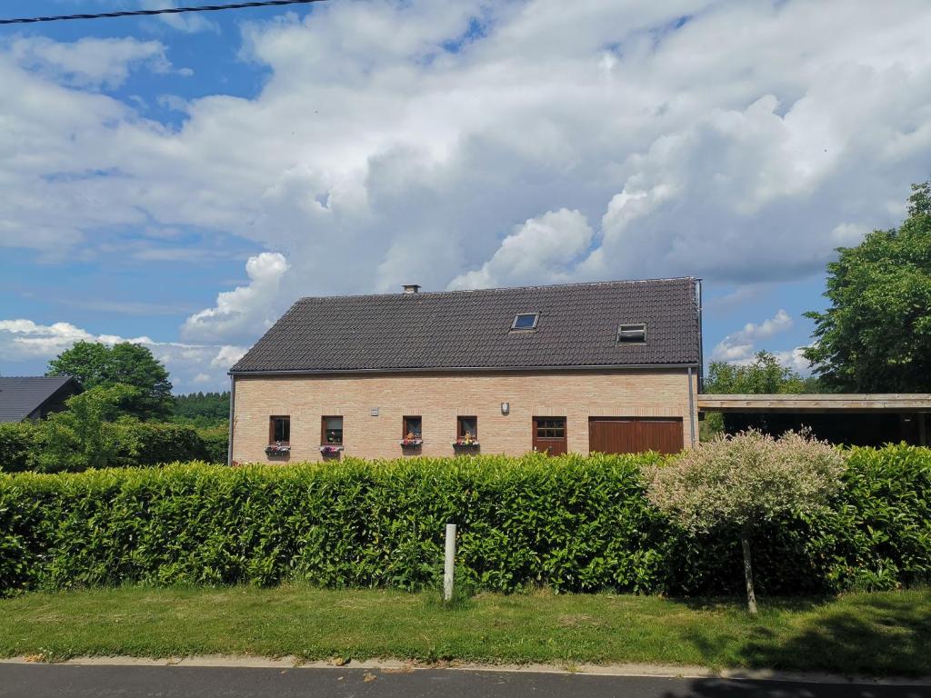 a brick building with a black roof next to a hedge at Mevazara guesthouse in Malmedy