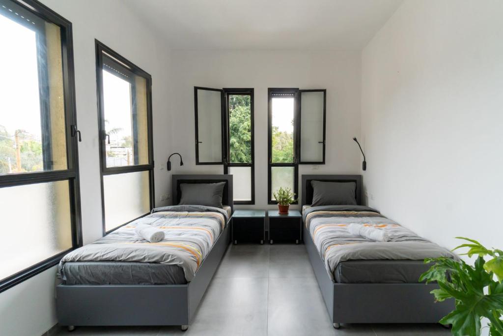 three beds in a room with windows at Nahal Oz 33 in Tel Aviv