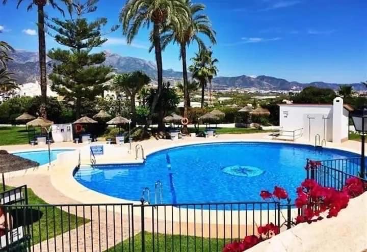 uma grande piscina com palmeiras e montanhas ao fundo em Shangri-La Punta Lara em Nerja