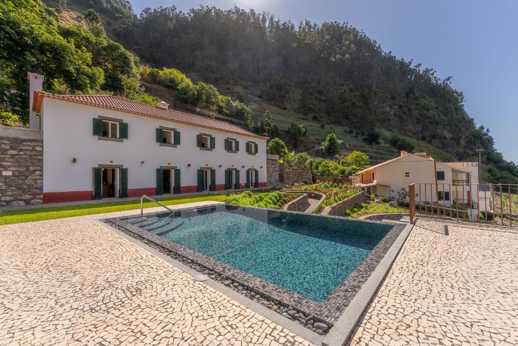 une maison avec une piscine en face d'une montagne dans l'établissement Solar dos Reis by An Island Apart, à Ribeira Brava