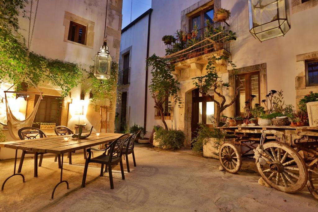 a patio with a wooden table and chairs and a carriage at Alla Giudecca in Siracusa