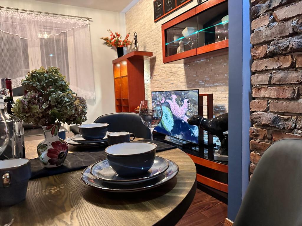 - une table à manger avec des bols et des assiettes dans l'établissement Be Inn - Luxury Apartment Gliwice, à Gliwice