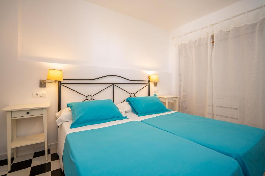 ein blaues Bett mit zwei blauen Kissen in einem Schlafzimmer in der Unterkunft Mirada II - Formentera Break in Es Pujols
