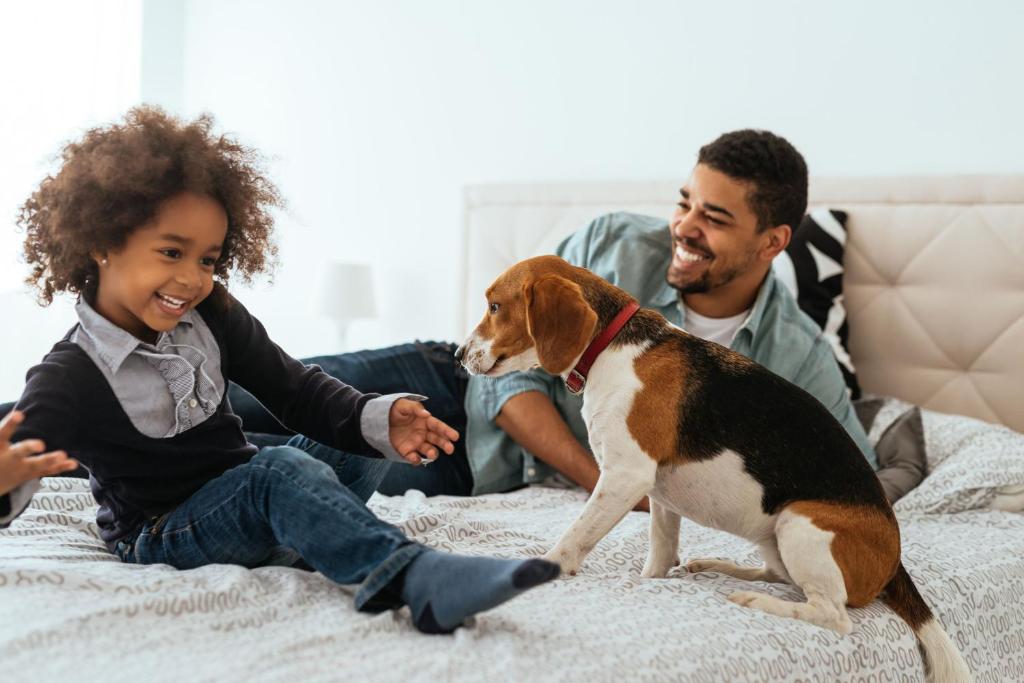 a man and a girl playing with a dog on a bed at Citadines Ramblas Barcelona in Barcelona