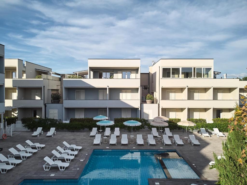 an apartment building with a pool and chairs and umbrellas at Golden Apartments in Marina di Cecina