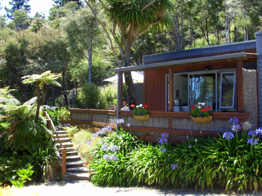 ein winziges Haus in einem Garten mit Blumen in der Unterkunft Cabbage Tree Chalet in Parapara 