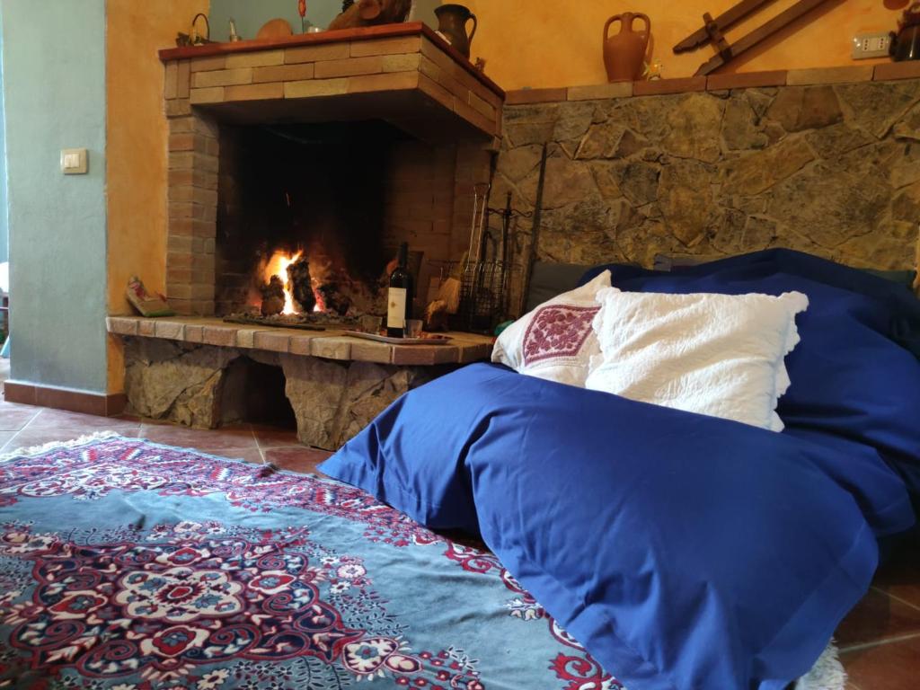 - un lit avec une couette bleue devant une cheminée dans l'établissement Sa ventana asulla, à San Vito