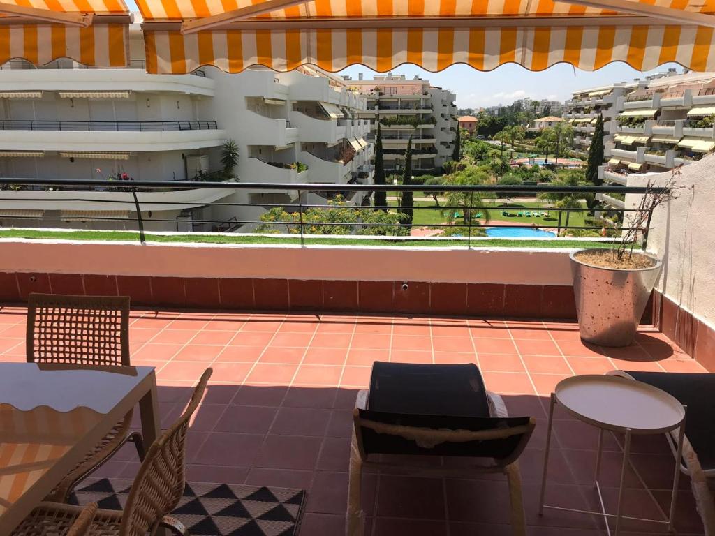 Un balcón con sillas y mesas en un edificio en Ático 2 Dormitorios en campo de Golf Guadalmina, Marbella, en Marbella