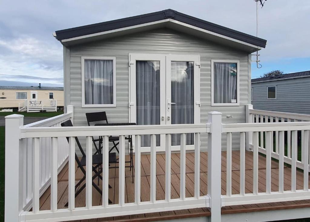 a tiny house with a white fence on a deck at Ty Gwyn Park in Abergele