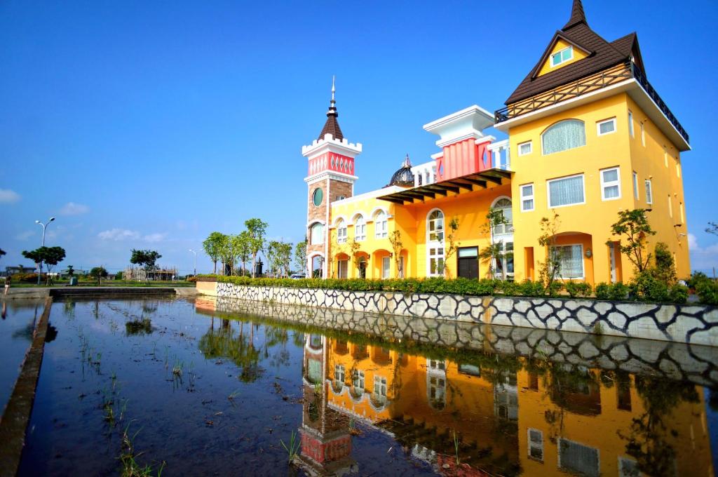 a yellow building with a clock tower next to a river at Jane Castle in Wujie