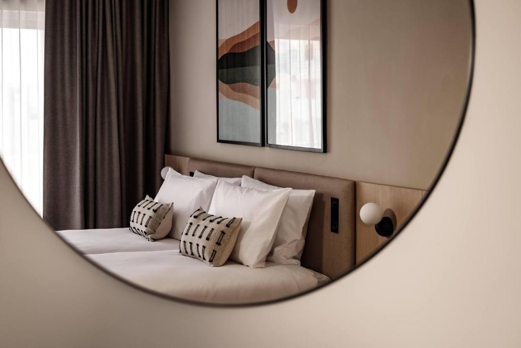 a bedroom with a bed with white pillows and a mirror at Strand Suites by NEU Collective in Il-Gżira