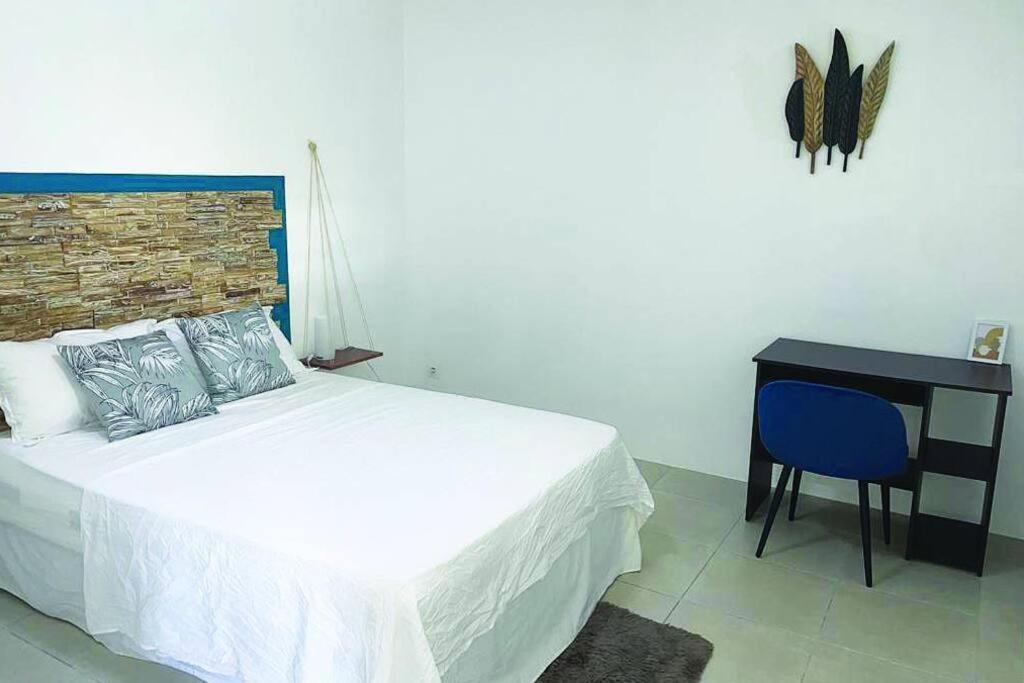 ein Schlafzimmer mit einem Bett und einem Schreibtisch mit einem blauen Stuhl in der Unterkunft Bel appartement dans écrin de verdure in Le Lamentin