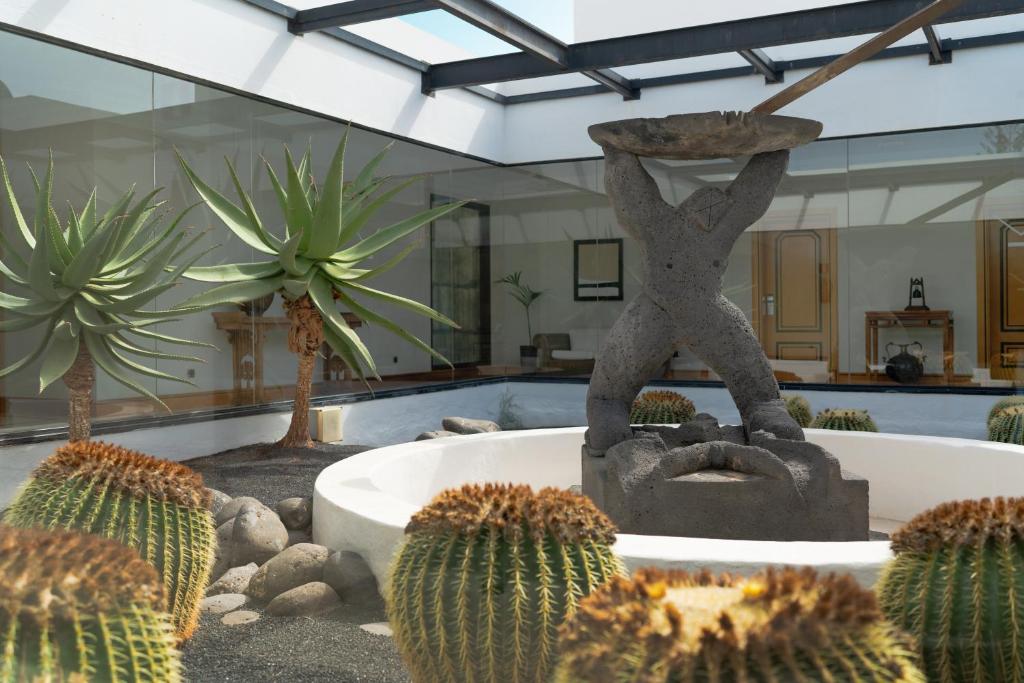 a statue of a person standing on a rock next to cactus at Villa VIK - Hotel Boutique in Arrecife