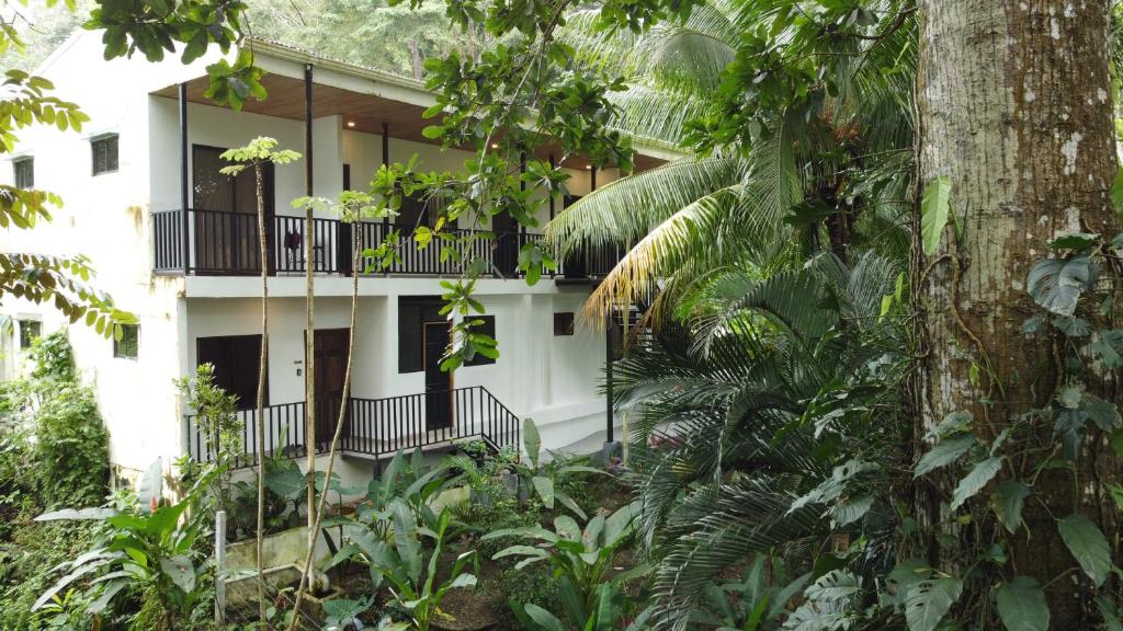 a white building with a balcony in the forest at Riverside Apartments - Walk to the Beach in Santa Teresa! Newly Renovated! in Santa Teresa Beach