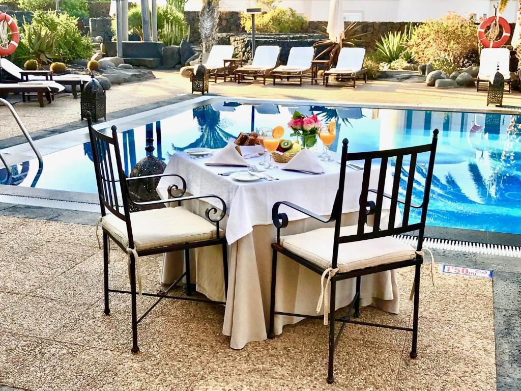 a table in front of a swimming pool at Villa VIK - Hotel Boutique in Arrecife