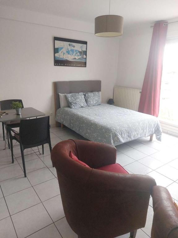 a bedroom with a bed and a couch and a table at Residence d'Anjou - Grand studio avec balcon et parking privatif in Perpignan