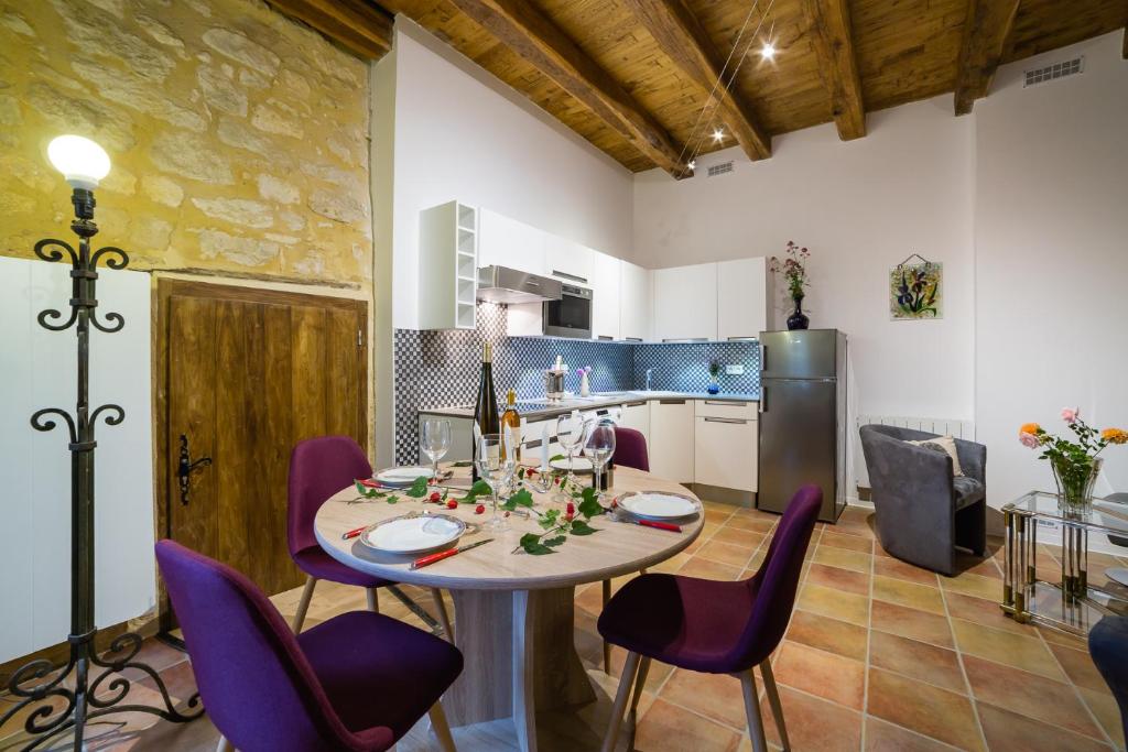 a kitchen and dining room with a table and purple chairs at Au coeur de Beynac, une maison de caractère avec jardin terrasse in Beynac-et-Cazenac