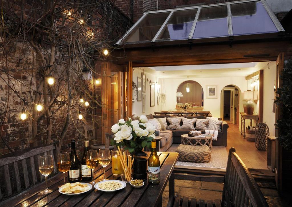 uma sala de estar com uma mesa com garrafas de vinho e flores em Dolls House - Luxury Townhouse *sleeps 10* em Henley on Thames