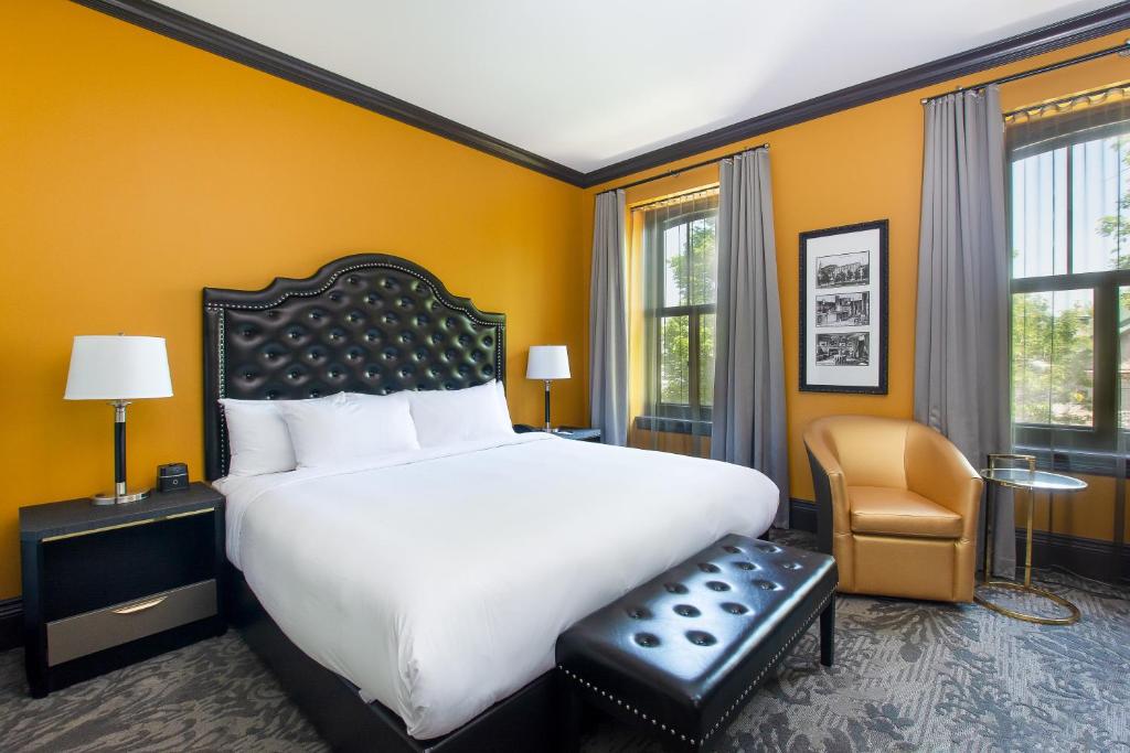 a bedroom with a large white bed and a chair at Hotel Clarendon in Quebec City