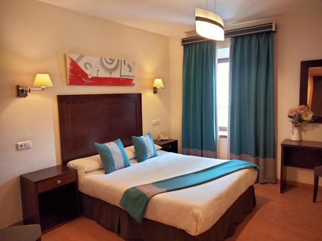 a hotel room with a large bed with blue pillows at Hotel & Spa PLAZA Arriate in Arriate