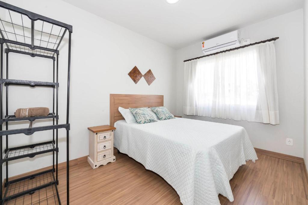 a white bedroom with a bed and a window at DOÑA ALZIRA in Bombinhas